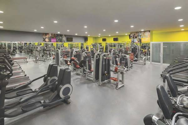 Fitnesscenter des Wyndham Grand Izmir Ozdilek Hotels mit vielen Geräten und gelben Wänden.