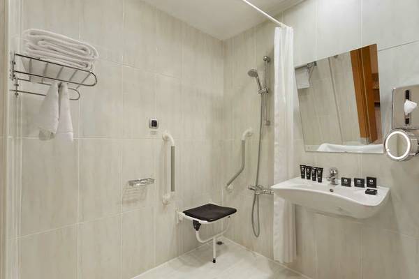 Behindertengerechtes Badezimmer im Wyndham Grand Izmir Ozdilek Hotel mit Toilettensitz, Handläufen und Duschbereich.
