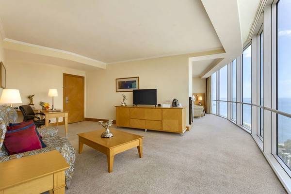 Innenansicht einer Hotelsuite im Wyndham Grand Izmir Ozdilek mit großem Fenster und Meerblick.