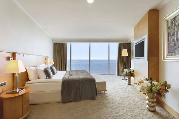 Hotelzimmer mit Meerblick im Wyndham Grand Izmir Ozdilek, mit großen Fenstern und Blick auf das Meer.