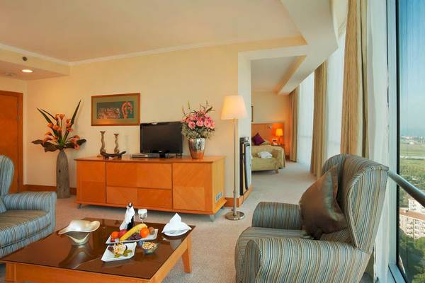 Ein Hotelzimmer des Wyndham Grand Izmir Ozdilek mit Wohnzimmerbereich, Fernseher und Frühstückstisch.