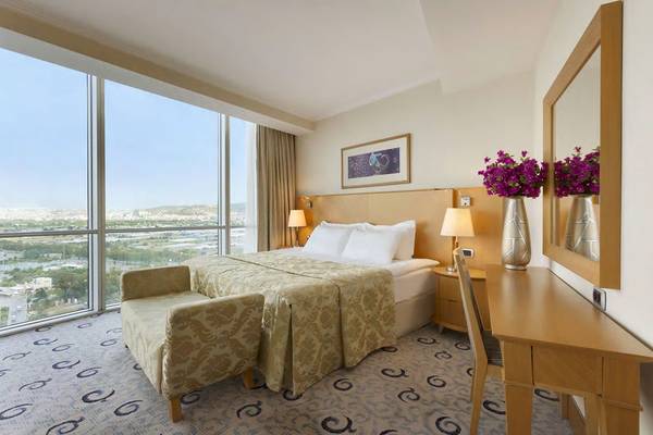 Wyndham Grand Izmir Ozdilek Hotelzimmer mit großem Fenster, Bett, Dekor und Aussicht auf die Stadt.