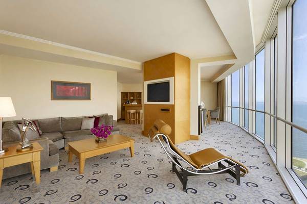 Ein modernes Hotelzimmer mit Meerblick, Sitzecke, Fernseher und großer Fensterfront.