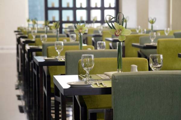 Restaurant im Tower Plaza Hotel Dubai mit gedeckten Tischen und grünen Stühlen.