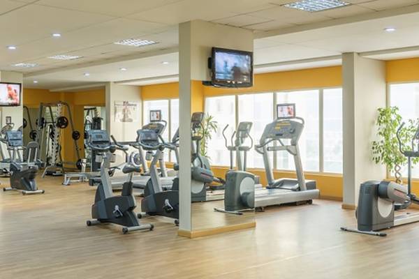 Fitnessstudio im Tower Plaza Hotel Dubai mit vielen Geräten und Fernsehern an der Wand.