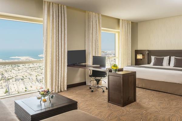 Zimmer im Tower Plaza Hotel Dubai mit Schreibtisch, Fernseher und Meerblick.