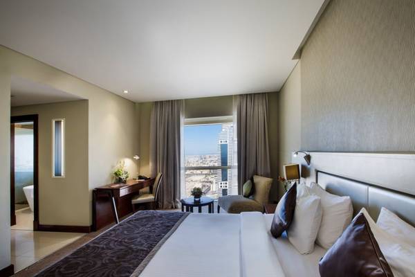 Innenansicht eines Zimmers im Tower Plaza Hotel Dubai mit Bett, Schreibtisch und Ausblick.