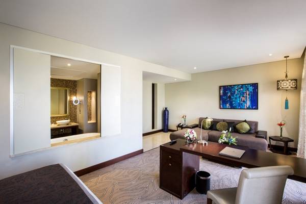Innenansicht der Suite im Tower Plaza Hotel Dubai mit Schreibtisch, Sofa und Badezimmerspiegel.