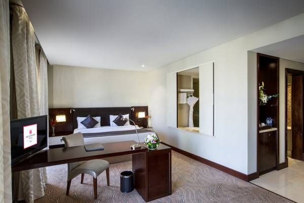 Innenansicht eines Hotelzimmers im Tower Plaza Hotel Dubai mit Bett, Schreibtisch und Fernseher.