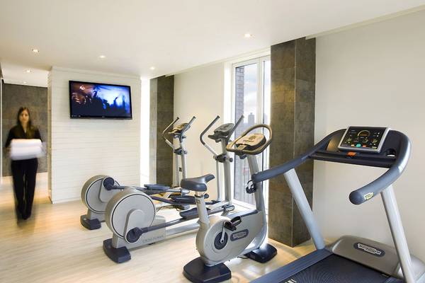 Fitnessraum im H10 London Waterloo mit Geräten und Fernseher an der Wand.