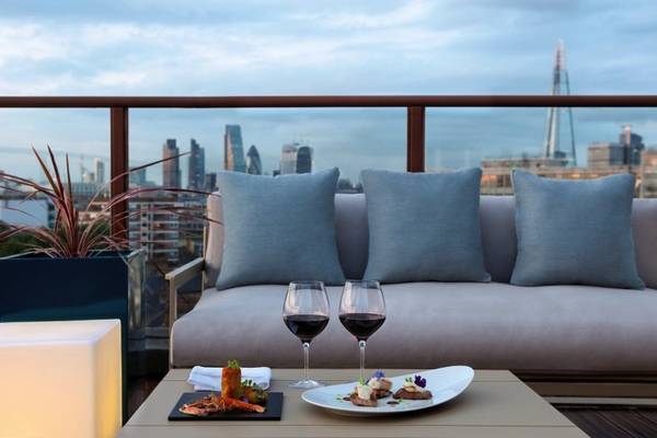 Aussicht auf die Londoner Skyline von der Terrasse des H10 London Waterloo Hotels mit Gerichten und Getränken.