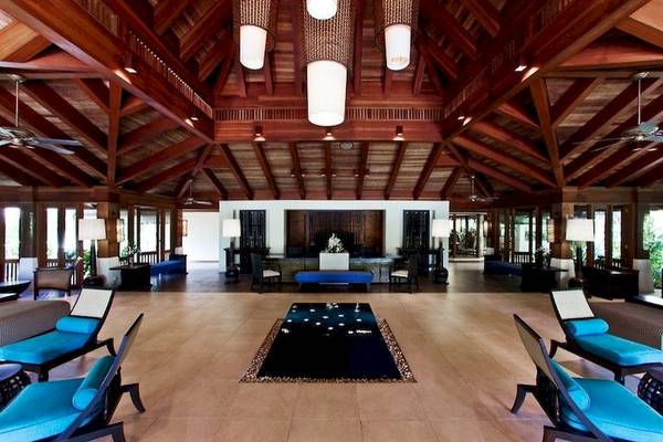 Lobby des Sheraton Maldives Full Moon Resort & Spa mit Holzdecken und blauen Möbeln.