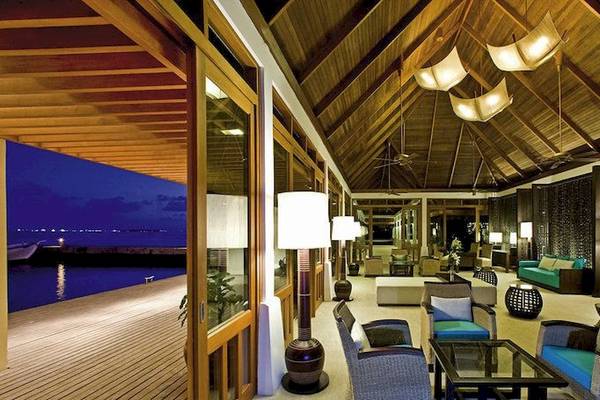 Lobby des Sheraton Maldives Full Moon Resort & Spa mit Blick auf das Wasser und modernen Möbeln.