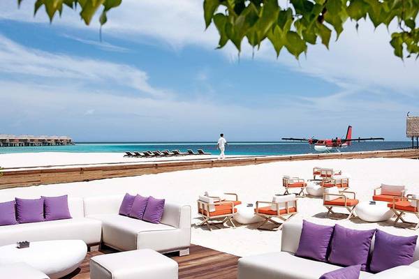 Außenbereich des Constance Moofushi Maldives mit Lounge-Sesseln und Blick auf den Strand.
