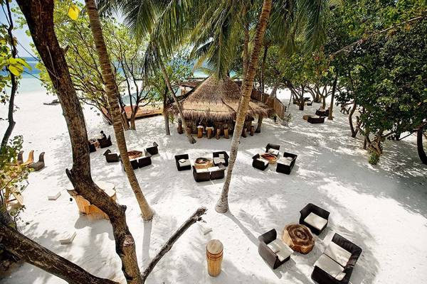 Luftaufnahme des Constance Moofushi Maldives Strand-Lodges mit Strohhütte und Loungemöbeln auf weißem Sand