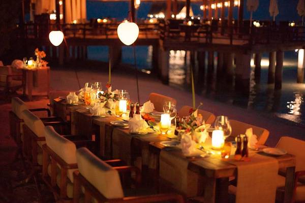 Abendessen am Wasser im Constance Moofushi Maldives mit gedecktem Tisch und Kerzenlicht.