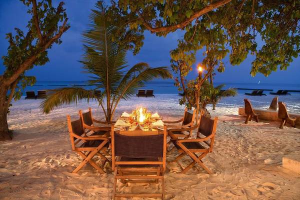 Abendessen am Strand im Constance Moofushi Maldives mit gedecktem Tisch unter Palmen.