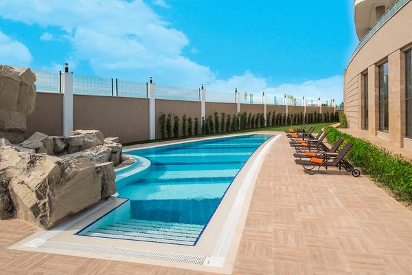 Ein Swimmingpool am Aska Lara Resort & Spa mit Liegestühlen und einer gepflasterten Terrasse.