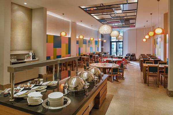 Innenansicht des Frühstücksraums im Aska Lara Resort & Spa mit farbenfrohen Wänden und modernen Möbeln.