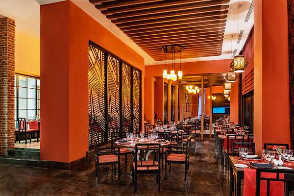 Innenansicht eines Hotels mit Restaurantbereich, Tischen und Stühlen, gedeckten Tischen und geometrischen Mustern an den Wänden.