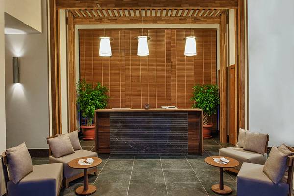Empfangsbereich des Aska Lara Resort & Spa mit Holzwänden, gepolsterten Sesseln und einem Empfangstresen.