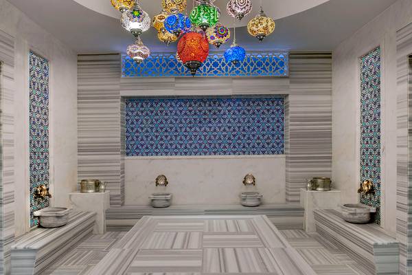 Innenansicht des Aska Lara Resort & Spa Hammam mit farbigen Lampen und Marmorboden.