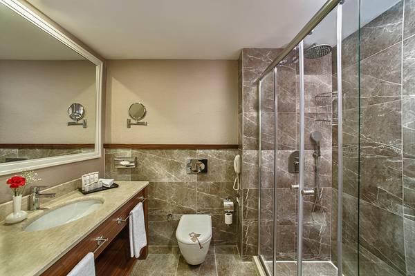Badezimmer des Aska Lara Resort & Spa mit Waschbecken, Spiegel, Toilette und Duschkabine.