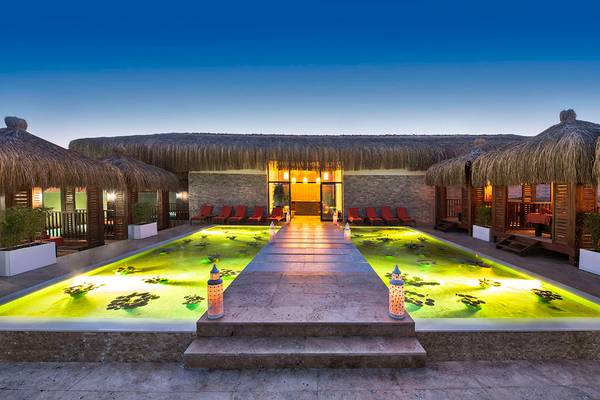 Außenbereich des Aska Lara Resort & Spa mit grünem Wasserlauf und roten Sonnenliegen.