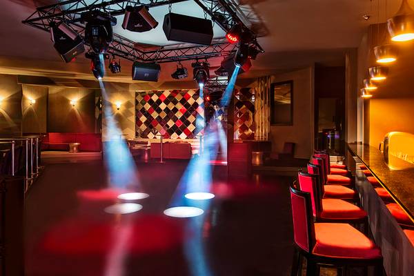 Ein Nachtclub mit roten Sitzen, einer Bar und Scheinwerferlicht.