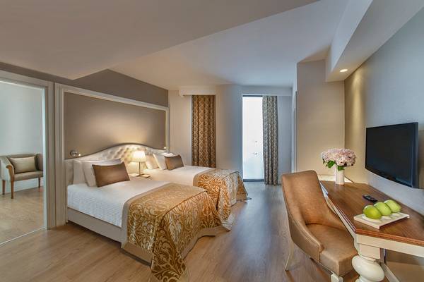 Zimmer im Aska Lara Resort & Spa mit zwei Betten, Schreibtisch und Fernseher.