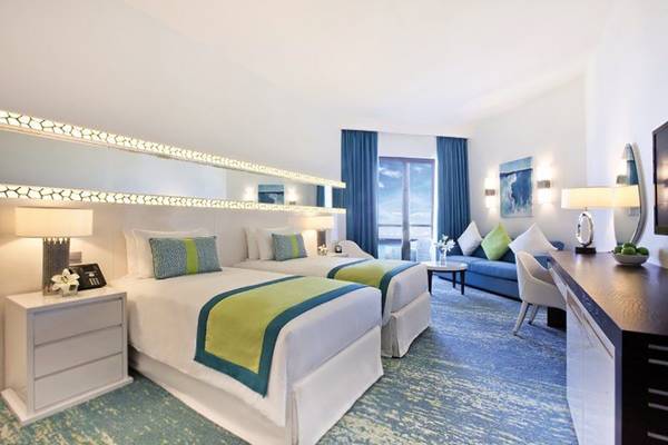 Doppelbettzimmer im JA Ocean View Hotel mit modernen Möbeln und Aussichtsfenstern.