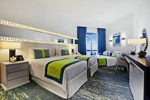 Doppelbettzimmer im JA Ocean View Hotel mit Meerblick, modernen Möbeln und Dekor.