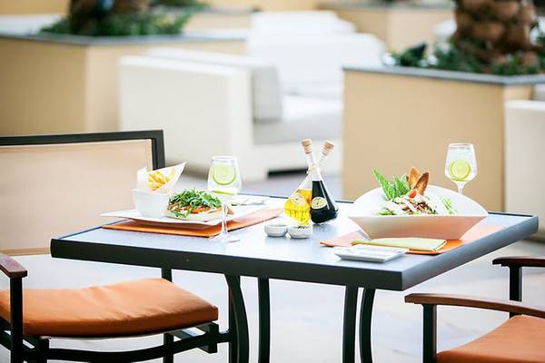 Gedeckter Tisch auf der Terrasse des JA Ocean View Hotels mit Salat, Öl und Getränken.