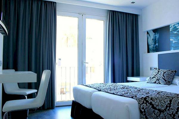 Doppelzimmer im BG Hotel Nautico Ebeso mit zwei Betten, Schreibtisch, Stühlen und Glastür.