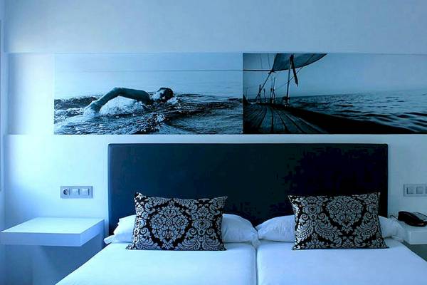 Schlafzimmer im BG Hotel Nautico Ebeso mit zwei Einzelbetten, Dekor und Bildern am Kopfende.