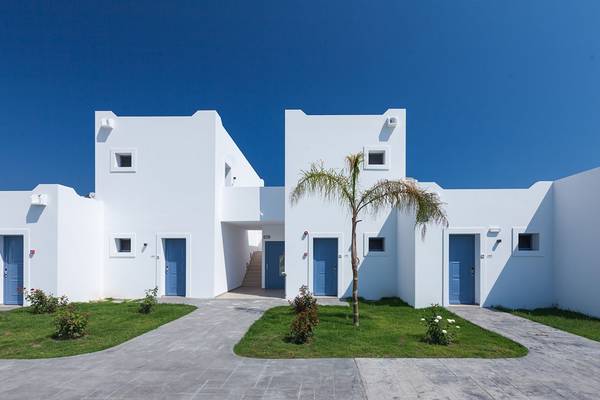 Außenansicht des Aeolos Beach Hotel auf Kos mit weißen Gebäuden und blauen Türen.