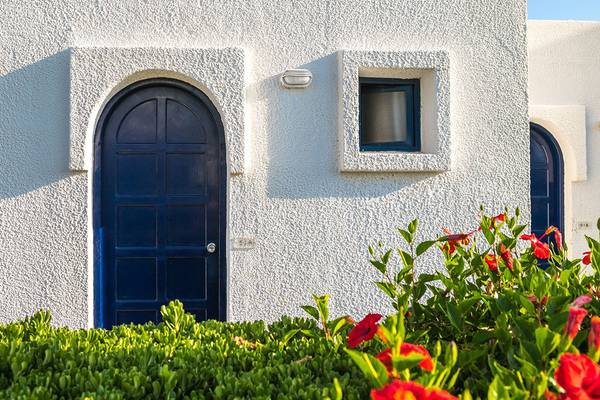 Eingang des Aeolos Beach Hotel - Kos mit blauer Tür und rotem Blumenbusch davor