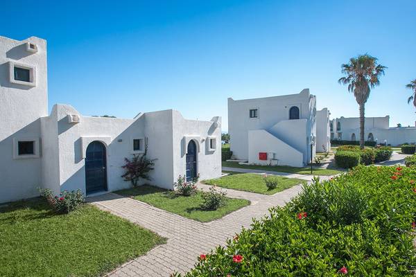 Außenansicht des Aeolos Beach Hotel in Kos mit weißen Gebäuden und gepflegtem Garten.