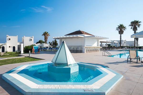 Poolbereich des Aeolos Beach Hotels auf Kos mit einem Brunnen und umliegenden Gebäuden.