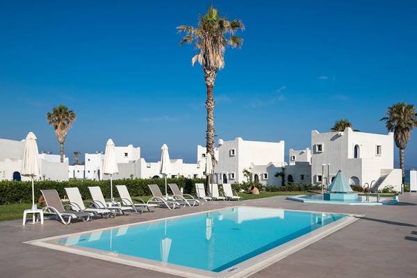 Poolbereich des Aeolos Beach Hotels auf Kos mit weißen Liegen und Palmen