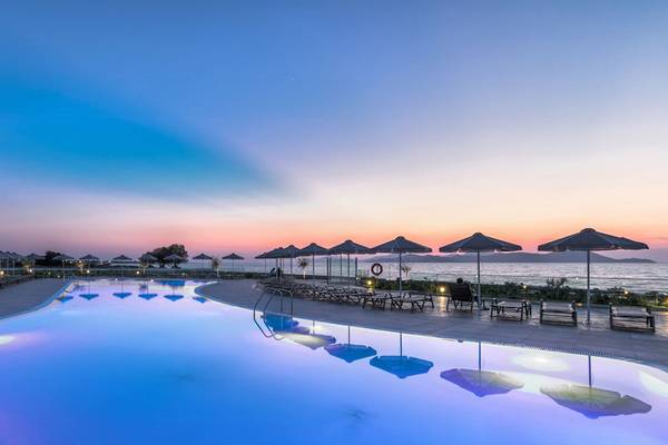 Außenpool des Aeolos Beach Hotels in Kos bei Sonnenuntergang mit Sonnenliegen und Sonnenschirmen