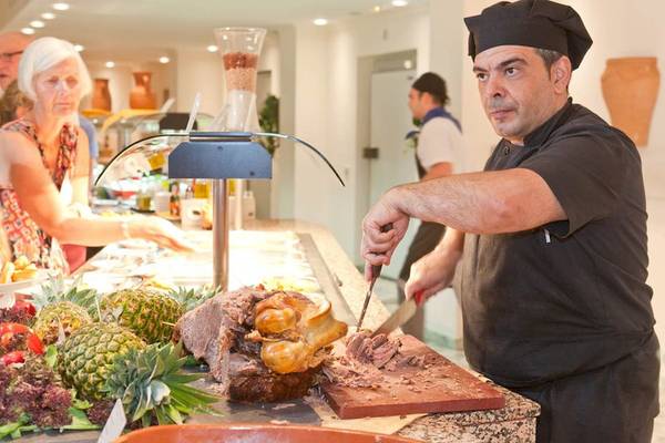 Ein Koch schneidet Fleisch auf einem Schneidebrett im Hotel Moon Dreams Coral Beach.