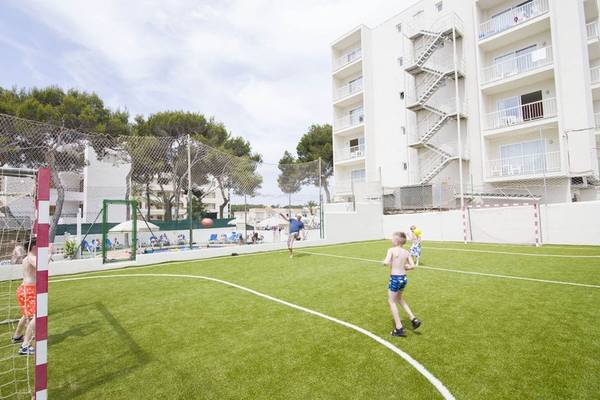 Kinder spielen Fußball auf einem Platz vor dem Moon Dreams Coral Beach Hotel.
