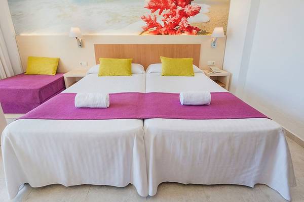 Doppelzimmer im Moon Dreams Coral Beach Hotel mit zwei Betten, weißen Laken, pinken Überwürfen, gelben Kissen und einer Wandmalerei.