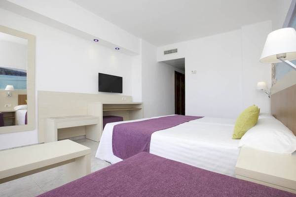 Hotelzimmer im Moon Dreams Coral Beach Hotel mit zwei Betten, Fernseher und Schreibtisch.