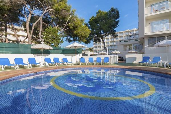 Poolbereich im Hotel Moon Dreams Coral Beach mit Liegen und Sonnenschirmen, umgeben von Bäumen und einem klaren Himmel.