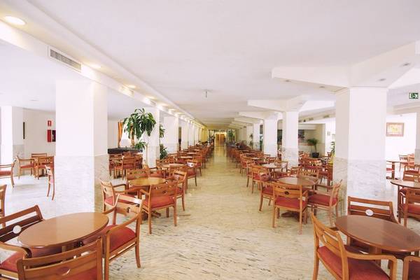 Helles Restaurant im Hotel Moon Dreams Coral Beach mit Tischen und Stühlen, umgeben von Pflanzen.