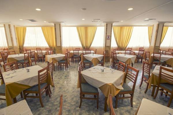 Innenansicht des Restaurants des Moon Dreams Coral Beach Hotels mit gedeckten Tischen und Stühlen.