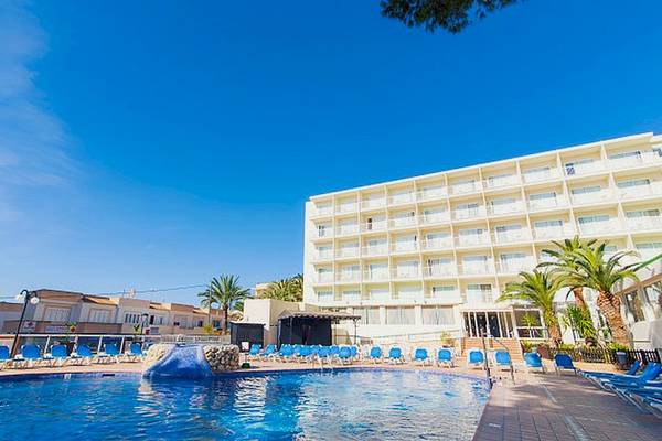 Hotel Moon Dreams Coral Beach mit Pool und Liegen unter blauem Himmel und Palmen im Hintergrund.
