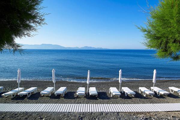 Außenbereich des Dimitra Beach Hotel & Suites mit Lounge-Sesseln am Strand.